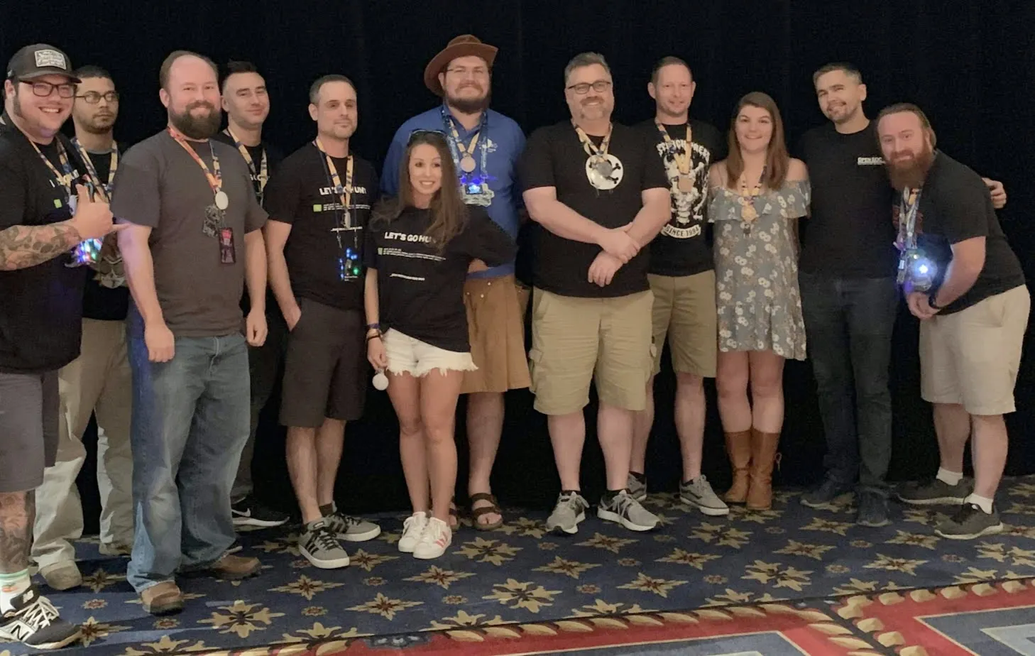 Group photo of about a dozen people wearing conference lanyards and badges